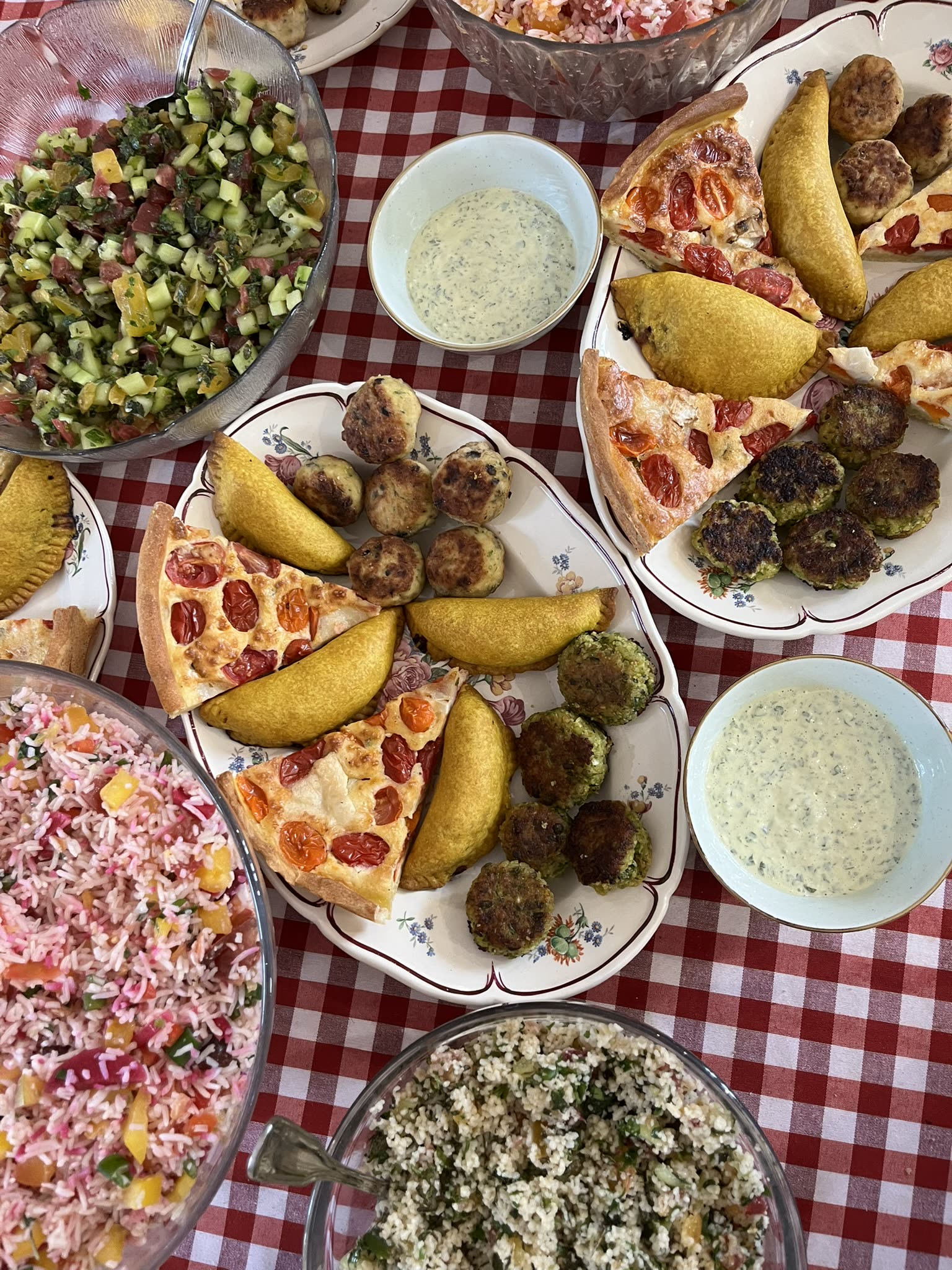 Table de réception garnie : tourtes aux tomates, falafels, salades et sauces maison